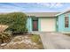 Front view of a light teal home with attached garage and landscaping at 255 Boundary Blvd # 104, Rotonda West, FL 33947