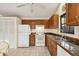 Kitchen with wood cabinets, white appliances, and granite countertops at 255 Boundary Blvd # 104, Rotonda West, FL 33947