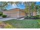 Tan house with three-car garage, lush landscaping, and walkway at 2888 Myakka Creek Ct., Port Charlotte, FL 33953