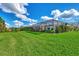 Large backyard with a screened patio, lush lawn, and tropical landscaping at 3283 Osprey Ln, Port Charlotte, FL 33953