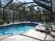 Inviting pool area with screened enclosure, lounge chairs, and lush landscaping at 380 Hoffer St, Port Charlotte, FL 33953