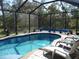 Inviting pool area with screened enclosure, lounge chairs, and lush landscaping at 380 Hoffer St, Port Charlotte, FL 33953