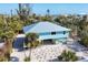 Aerial view of a light blue house with metal roof and tropical landscaping at 396 N Gulf Blvd, Placida, FL 33946