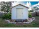 White storage shed with a single door, stone border, and potted plants at 97 Lakeview Ln, Englewood, FL 34223