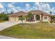 Tan house with three-car garage, palm trees, and a manicured lawn at 116 Hercules Dr, Rotonda West, FL 33947