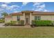 Tan single-story home with a brown tile roof, neatly landscaped lawn, and a paved walkway to the front door at 13048 Creekside Ln, Port Charlotte, FL 33953