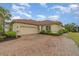 Attached garage with a tan exterior matching the house and a brick paved driveway at 13048 Creekside Ln, Port Charlotte, FL 33953