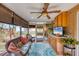 Bright sunroom features wicker furniture, ceiling fan and built-in cabinets at 1780 Morning Dove Ln, Englewood, FL 34224