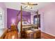 Main bedroom with four-poster bed, hardwood floors, and purple accent wall at 6153 Pennell St, Englewood, FL 34224