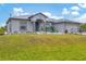 Single story home with gray metal roof, light gray walls, and a blue front door at 6153 Pennell St, Englewood, FL 34224
