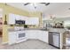 White kitchen with stainless steel appliances and light tile flooring at 6153 Pennell St, Englewood, FL 34224
