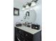 Dark vanity with a round mirror above the sink at 672 Circlewood Dr # V9, Venice, FL 34293