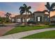Beautiful home featuring a landscaped front yard, palm trees, and a brick driveway at sunset at 10705 Tarflower Dr, Venice, FL 34293