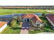 Aerial view of a home with a tile roof overlooking a golf course and lake at 10705 Tarflower Dr, Venice, FL 34293