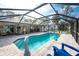 Relaxing pool with screened enclosure, patio furniture, and lush landscaping at 1651 Maria St, Englewood, FL 34223