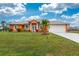 Attractive orange house with a large yard, two-car garage, and palm trees at 2194 Wenona Dr, North Port, FL 34288