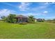 Spacious backyard with covered patio, lush landscaping, and large lawn at 26906 Weiskopf Dr, Englewood, FL 34223