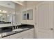 Bathroom with dark granite countertop, white cabinets, and a large mirror at 26906 Weiskopf Dr, Englewood, FL 34223