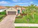 Tan house with brown garage door, landscaping, and palm trees at 26906 Weiskopf Dr, Englewood, FL 34223