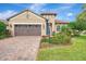 Tan house with brown garage door, landscaping, and palm trees at 26906 Weiskopf Dr, Englewood, FL 34223