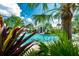 Community pool partially seen through tropical landscaping at 26906 Weiskopf Dr, Englewood, FL 34223