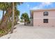 Pink building exterior with palm trees and a gravel driveway at 2805 N Beach Rd # B, Englewood, FL 34223