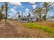 Home's backyard with unkempt grass and surrounding trees at 321 S Mango St, Englewood, FL 34223