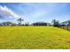 Large, manicured backyard with palm trees, with a screened patio in the distance at 3522 Fox Ter, Port Charlotte, FL 33981