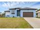 Newly built light blue house with a brown garage door and well-manicured lawn at 4220 Cape Haze Dr, Placida, FL 33946