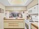 Kitchen with view into living room, white appliances, and wood cabinets at 4260 Placida Rd # 18C, Englewood, FL 34224