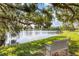 Serene lakeside view with bench, lush greenery, and shade trees at 610 Apple Ln, Englewood, FL 34223