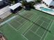 Aerial view of well-maintained tennis courts, adjacent to a pool and community buildings at 9700 Fiddlers Green Cir # 117, Rotonda West, FL 33947