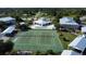 Aerial shot of tennis courts next to a pool, community center, and residential buildings at 9700 Fiddlers Green Cir # 117, Rotonda West, FL 33947
