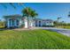 Well-maintained light blue home with mature palm trees and lush landscaping at 1061 Boundary Blvd, Rotonda West, FL 33947