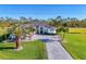 Light blue home with a paver driveway and front-entry two-car garage and mature palm trees at 1061 Boundary Blvd, Rotonda West, FL 33947