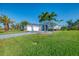 Light blue home with a three-car garage, paver driveway, and lush green lawn at 1061 Boundary Blvd, Rotonda West, FL 33947