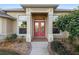 Inviting home exterior with a red double door and landscaping at 13575 Chenille Dr, Port Charlotte, FL 33981