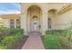 Welcoming front entry with arched doorway, brick walkway, and manicured landscaping at 14173 Myakka Pointe Dr, Port Charlotte, FL 33953