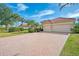 Two-car garage with herringbone brick driveway and lush landscaping at 14173 Myakka Pointe Dr, Port Charlotte, FL 33953