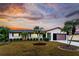 Single-story home with a landscaped yard and a sunset sky at 1505 Fireside St, Port Charlotte, FL 33952