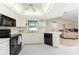 Kitchen with white cabinets, black appliances, and a view of the living room at 1600 Thomas St, Englewood, FL 34223