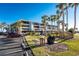 Condominium building with parking and an outdoor picnic area with grill and lush landscaping at 1701 Beach Rd # 404, Englewood, FL 34223