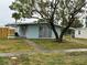 Light blue house with carport and a large tree in the front yard at 21179 Glendale Ave, Port Charlotte, FL 33952