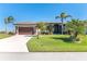 Single-story home with attached garage, lush landscaping, and palm trees at 214 W Pine Valley Ln, Rotonda West, FL 33947