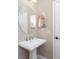 Modern bathroom with pedestal sink, round mirror, and updated fixtures at 26744 Weiskopf Dr, Englewood, FL 34223