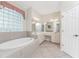 Bathroom with a large soaking tub, double vanity, and a glass block window at 276 Long Meadow Ln, Rotonda West, FL 33947