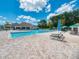 Beautiful community pool area with lounge chairs and umbrellas and a clear blue sky with puffy clouds at 3323 Grand Vista Ct # 201, Port Charlotte, FL 33953