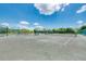 Community tennis court area with shaded benches and surrounding foliage against a blue sky with white clouds at 3323 Grand Vista Ct # 201, Port Charlotte, FL 33953