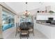 Dining area with a view of the screened-in pool, golf course and modern chandelier at 40 Bunker Pl, Rotonda West, FL 33947