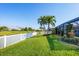 Lush backyard with a canal view, tropical palm trees, and a white picket fence at 429 Rotonda Cir, Rotonda West, FL 33947